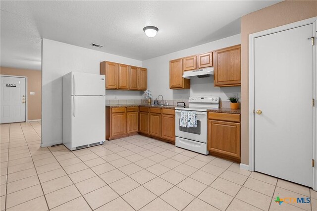 1413 Hopi Trl, Harker Heights, TX 76548 - kitchen with white appliances, under cabinet range hood, light tile patterned floors, brown cabinetry, and a textured ceiling