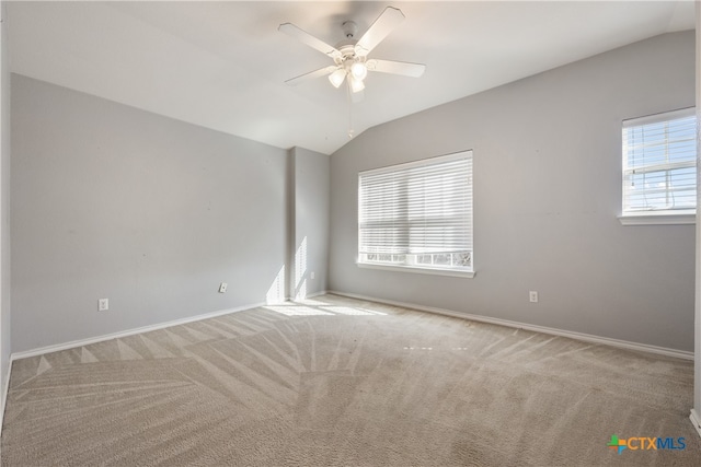 empty room with ceiling fan, lofted ceiling, light carpet, and a wealth of natural light