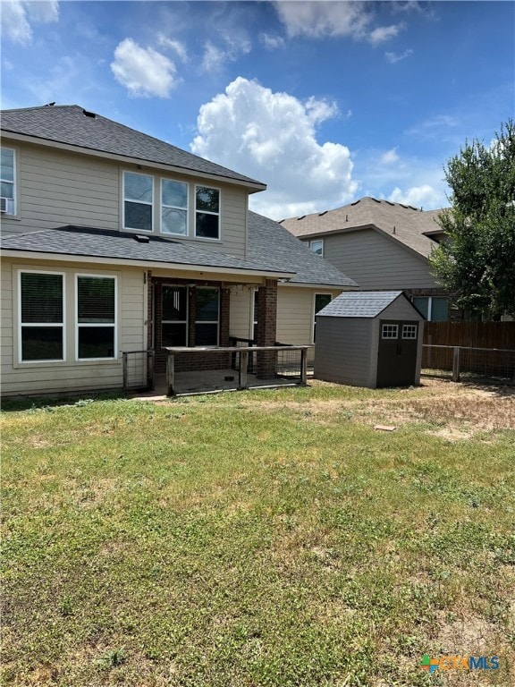 rear view of house featuring a yard and a shed