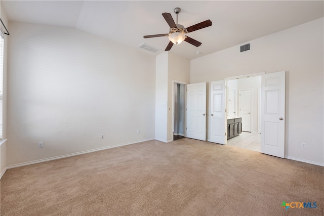 unfurnished bedroom featuring ensuite bathroom, ceiling fan, light colored carpet, and lofted ceiling