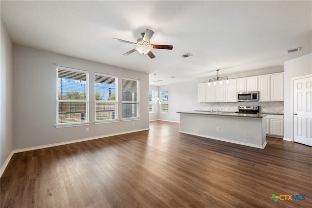 unfurnished living room featuring ceiling fan, sink, dark wood-type flooring, and a wealth of natural light