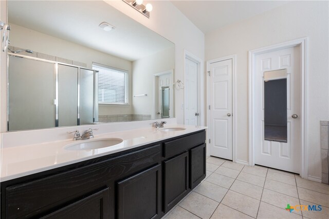 bathroom featuring tile patterned flooring, vanity, and a shower with door