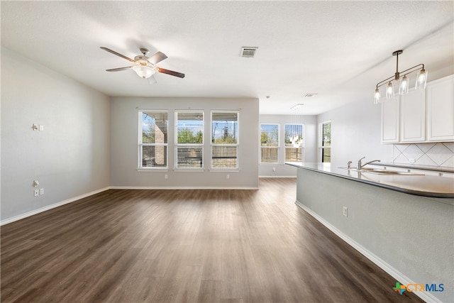 unfurnished living room featuring ceiling fan, dark hardwood / wood-style flooring, and sink