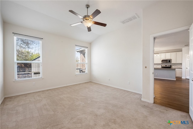 carpeted empty room featuring a wealth of natural light, lofted ceiling, and ceiling fan