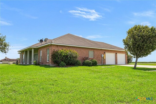 444 E Maxwell Ditch Rd, Port Lavaca, TX 77979 - view of home's exterior with a garage, concrete driveway, a lawn, and brick siding