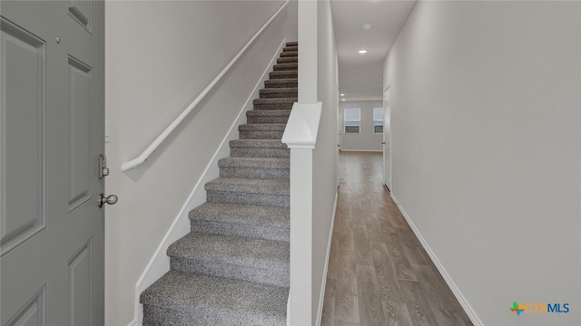 stairs with recessed lighting, wood finished floors, and baseboards