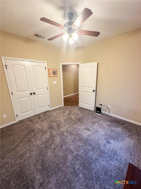 unfurnished bedroom featuring ceiling fan, dark carpet, and a closet