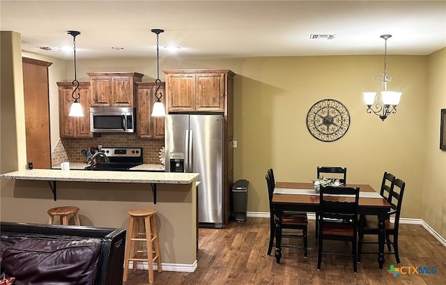 kitchen featuring a breakfast bar, tasteful backsplash, light stone counters, appliances with stainless steel finishes, and dark hardwood / wood-style flooring