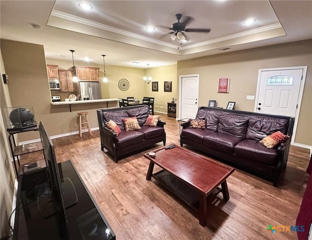 living room with a raised ceiling, crown molding, and hardwood / wood-style flooring