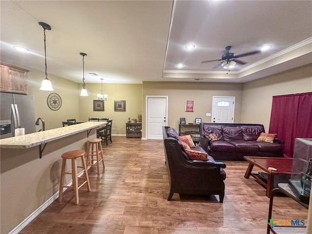 living room featuring sink, hardwood / wood-style flooring, ceiling fan, ornamental molding, and a raised ceiling