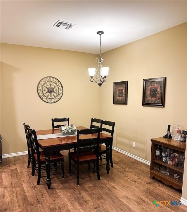 dining area with wood-type flooring and a chandelier