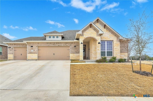 view of front of house with brick siding, a shingled roof, a garage, stone siding, and driveway