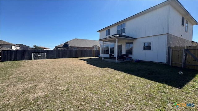 rear view of house featuring a yard, a fenced backyard, and brick siding