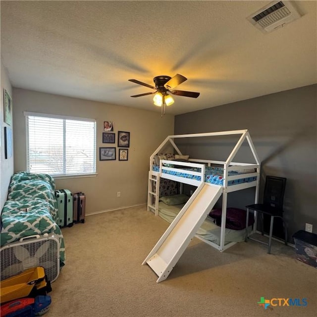 carpeted bedroom with visible vents, ceiling fan, a textured ceiling, and baseboards