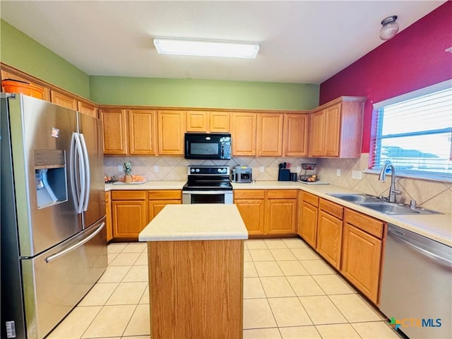 kitchen with a kitchen island, appliances with stainless steel finishes, light countertops, a sink, and light tile patterned flooring