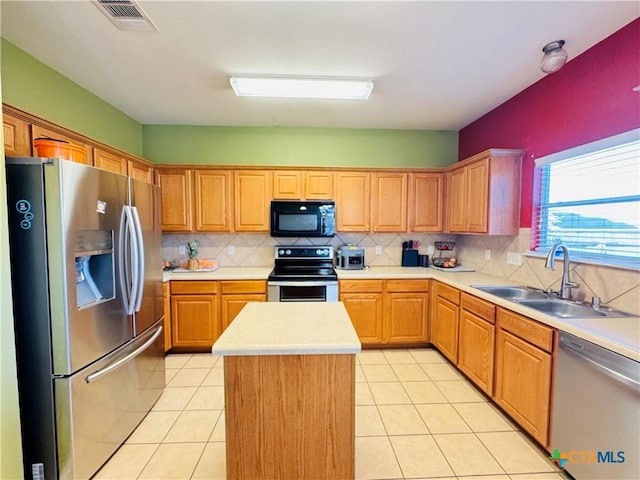 kitchen with stainless steel appliances, light countertops, visible vents, a sink, and a kitchen island