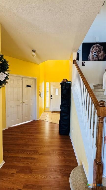 foyer with stairway, a textured ceiling, and wood finished floors