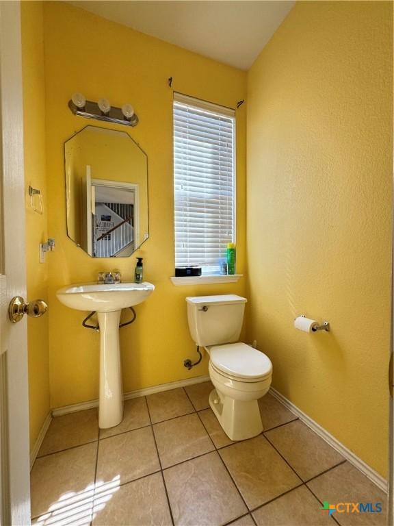 bathroom with baseboards, toilet, and tile patterned floors