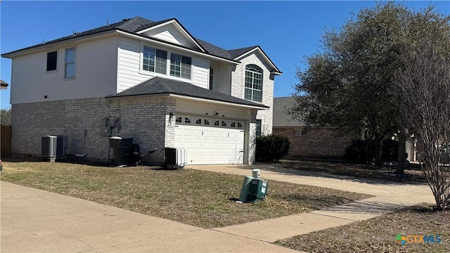 view of side of home with driveway, a garage, a yard, central AC, and brick siding