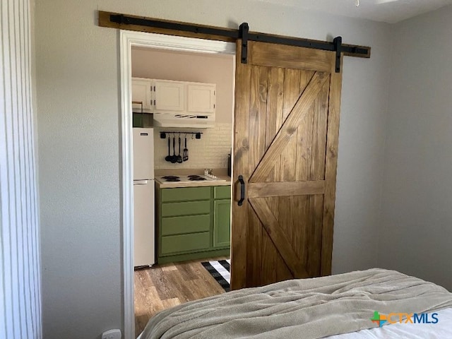 953 County Road 3351, Kempner, TX 76539 - bedroom with a barn door, light wood-style flooring, and freestanding refrigerator