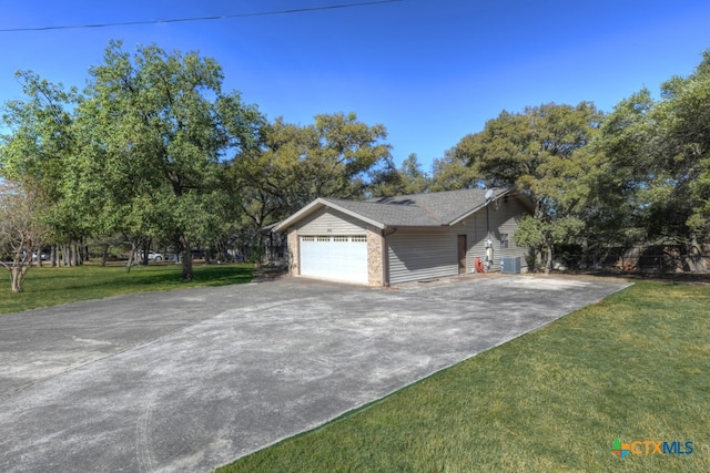 view of front of property featuring a front lawn, a garage, and central AC unit