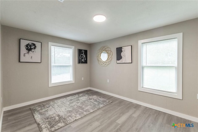 empty room with baseboards, wood finished floors, and plenty of natural light