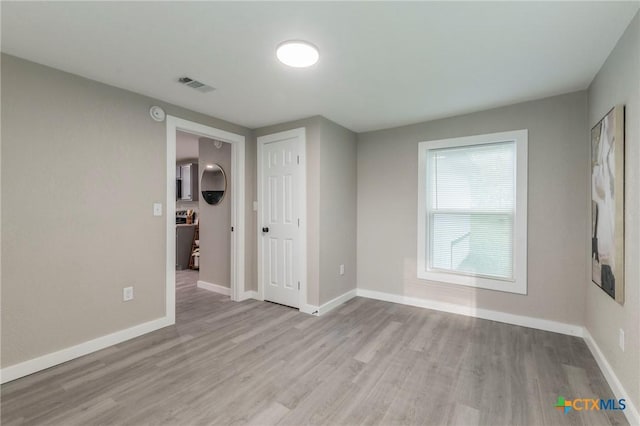 spare room featuring baseboards, visible vents, and wood finished floors
