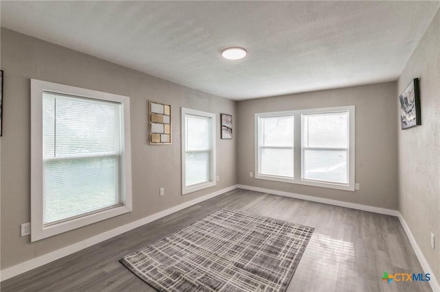 spare room with baseboards, wood finished floors, and a textured ceiling
