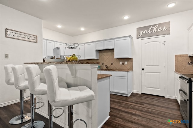 4505 Prewitt Ranch Rd, Killeen, TX 76549 - kitchen with a breakfast bar, dark wood-style flooring, white cabinets, decorative backsplash, and double oven range