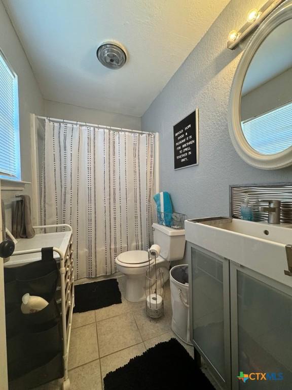 bathroom featuring toilet, tile patterned flooring, and walk in shower