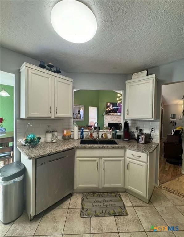 kitchen featuring sink, white cabinets, light tile patterned floors, and dishwasher