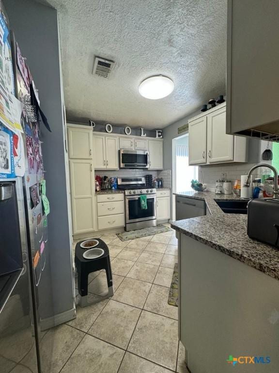 kitchen featuring white cabinetry, stainless steel appliances, sink, light tile patterned floors, and stone counters