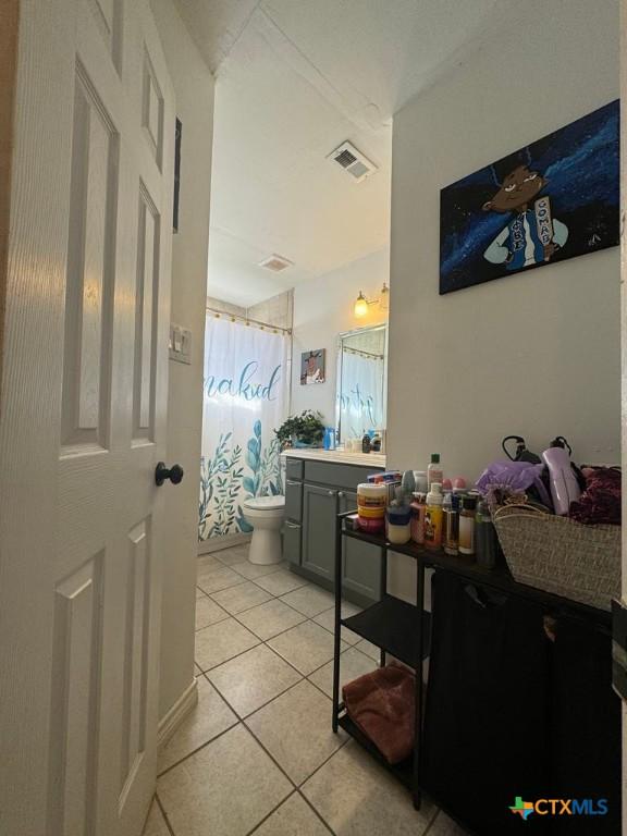 bathroom featuring toilet, vanity, walk in shower, and tile patterned flooring