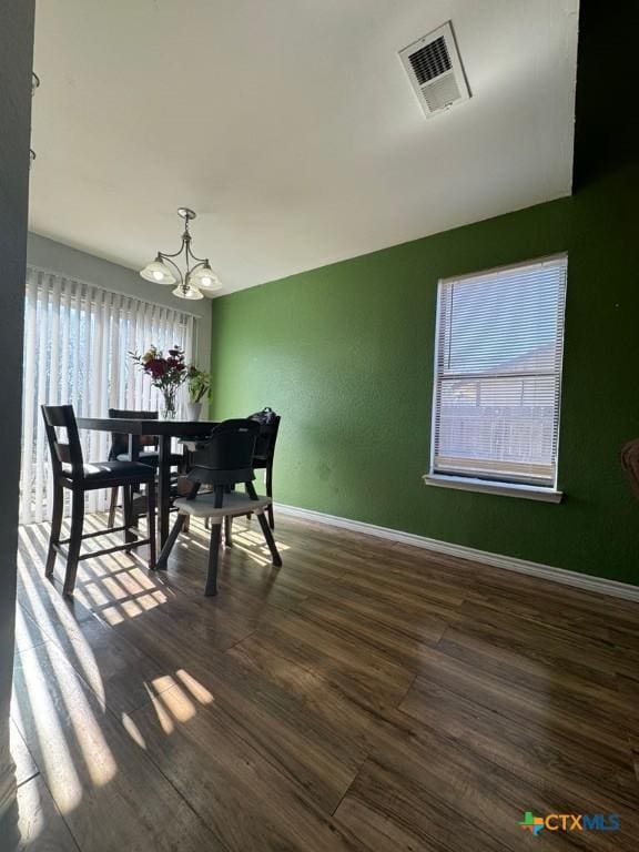 dining space featuring dark wood-type flooring and a chandelier