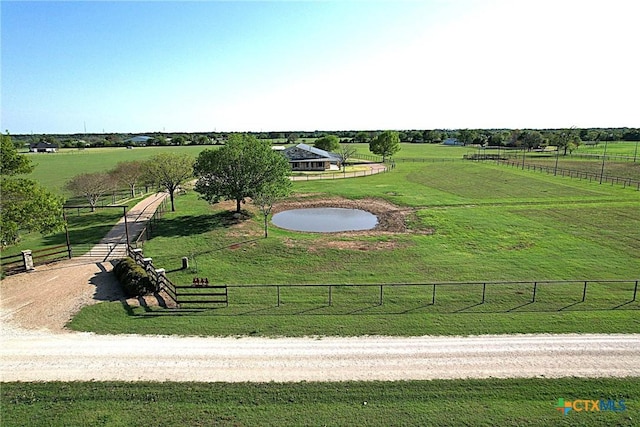 view of community featuring a rural view, a lawn, and fence