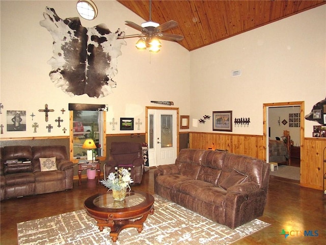 living room with high vaulted ceiling, wooden ceiling, ceiling fan, and wood walls