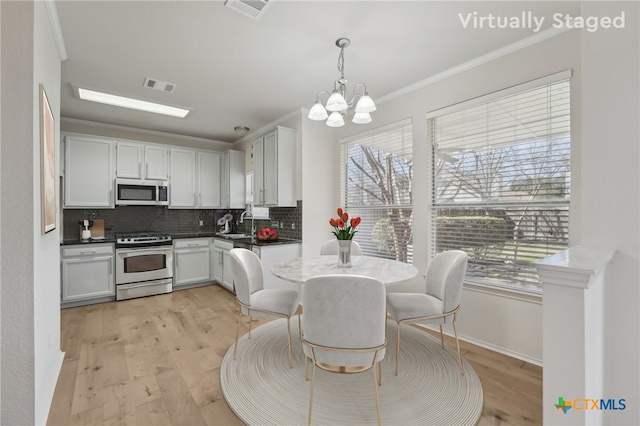 kitchen with stainless steel appliances, light wood-style floors, visible vents, and ornamental molding