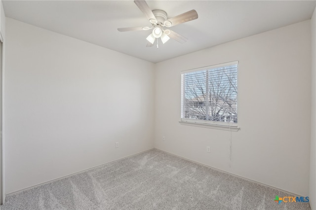 carpeted spare room featuring a ceiling fan