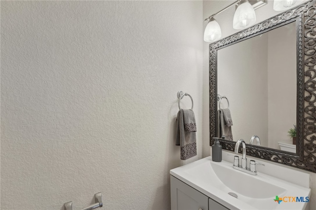 half bath with vanity and a textured wall