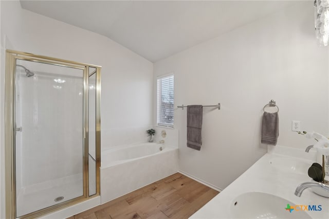 bathroom featuring lofted ceiling, wood finished floors, a shower stall, and a sink