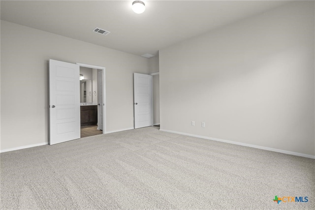 unfurnished bedroom featuring light colored carpet and ensuite bath