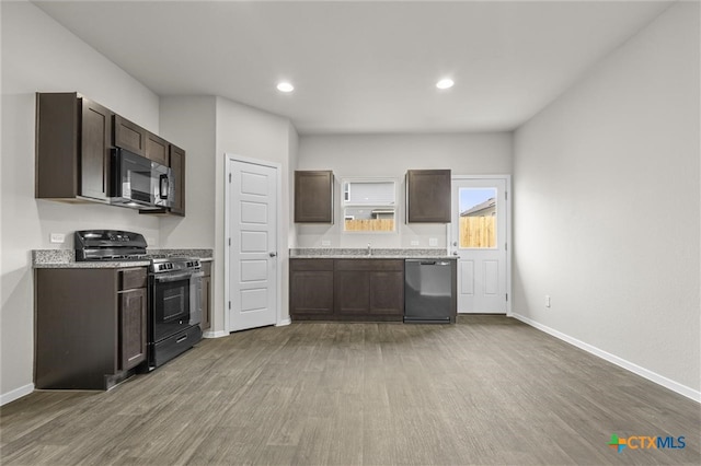 kitchen featuring dark brown cabinetry, black appliances, and hardwood / wood-style flooring