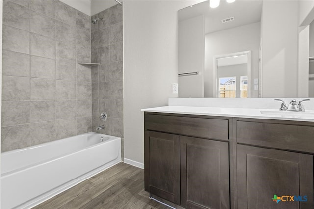 bathroom featuring wood-type flooring, vanity, and tiled shower / bath