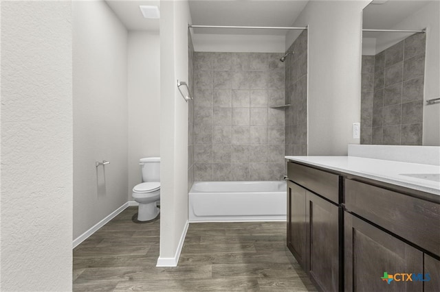 full bathroom featuring hardwood / wood-style floors, vanity, toilet, and tiled shower / bath