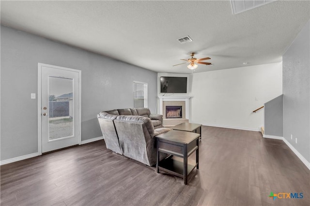 2506 Alamocitos Creek Dr, Killeen, TX 76549 - living room with dark wood finished floors, ceiling fan, a fireplace with raised hearth, baseboards, and a textured ceiling
