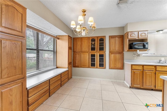 14311 Arrowood, San Antonio, TX 78233 - kitchen with black microwave, light countertops, light tile patterned flooring, a textured ceiling, and a chandelier