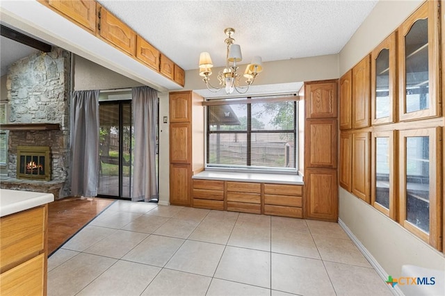 14311 Arrowood, San Antonio, TX 78233 - unfurnished dining area with light tile patterned floors, a chandelier, a textured ceiling, and a fireplace