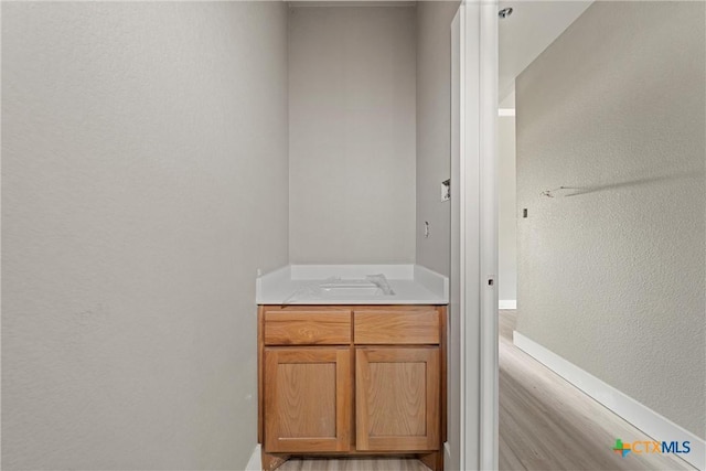 bathroom with baseboards, a textured wall, and vanity