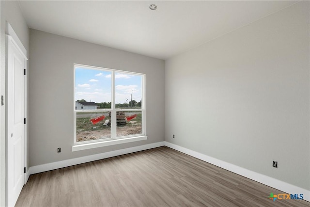 spare room featuring baseboards and wood finished floors