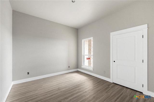 unfurnished room with baseboards and dark wood-style flooring